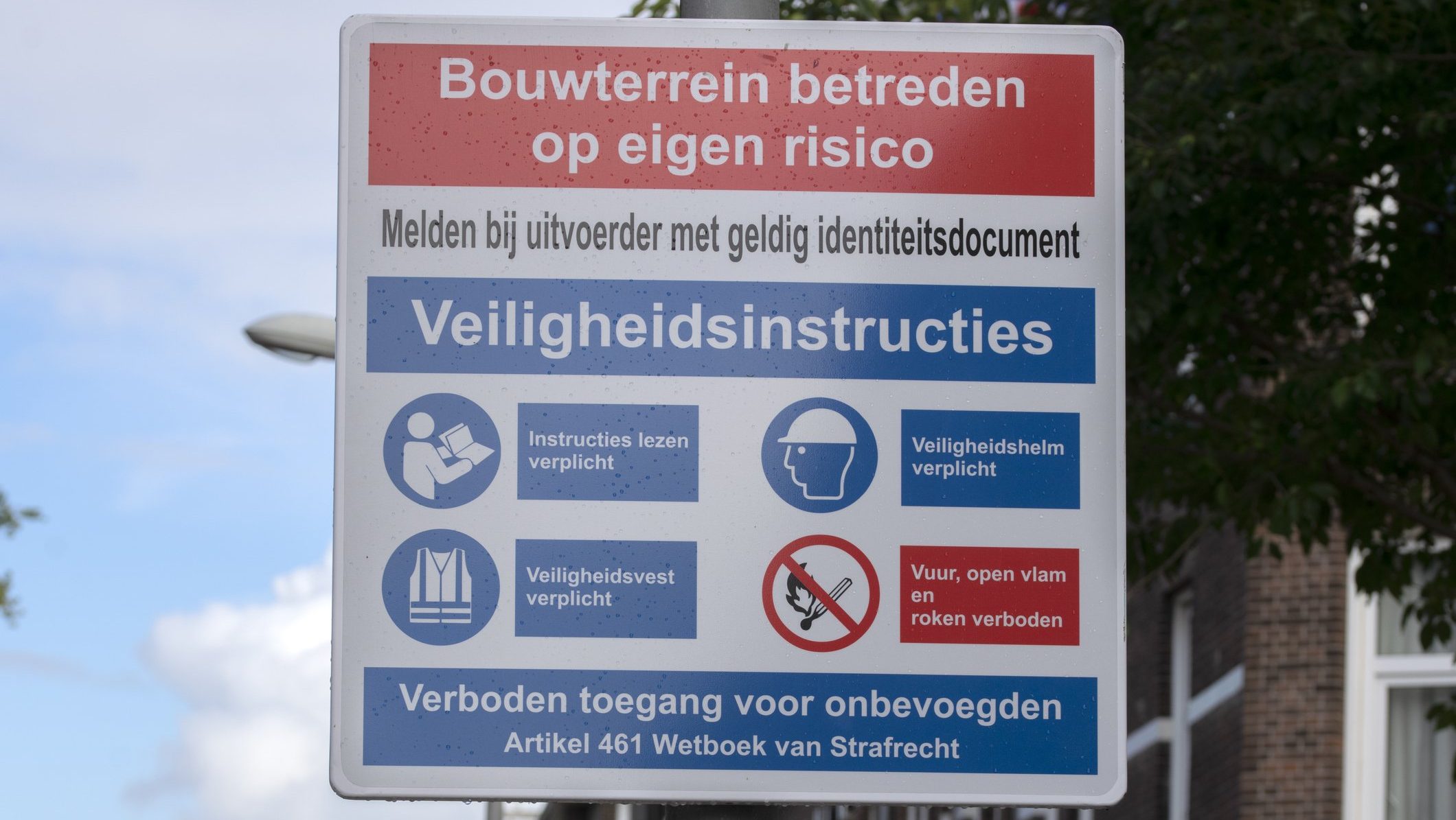 Waarschuwingsbord op bouwterrein met VCA-veiligheidsinstructies zoals helm- en hesjesplicht